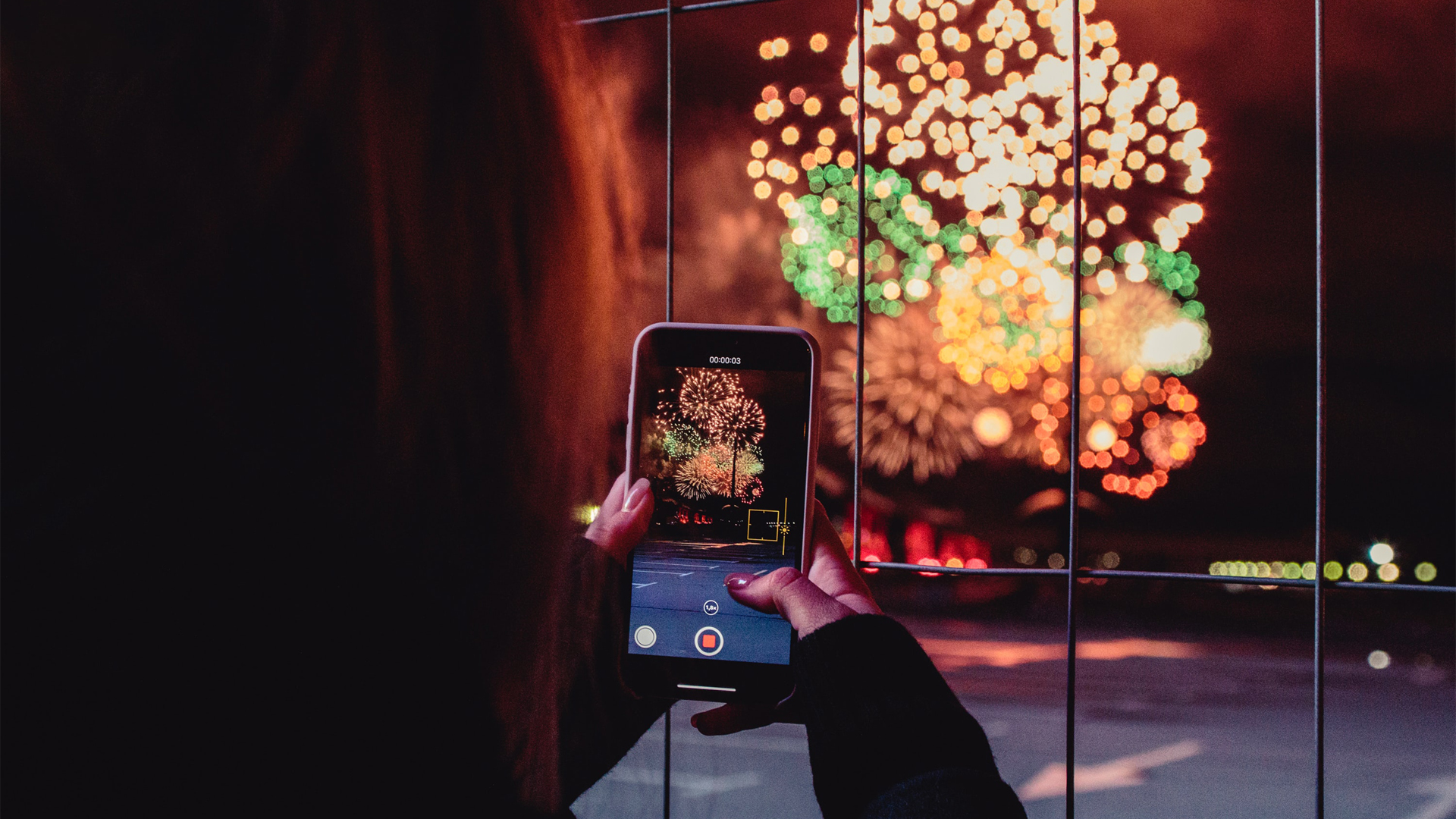 Woman capturing fireworks display on a phone