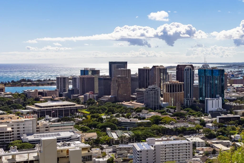 Picture of Downtown Honolulu taken at Pūowaina/Punchbowl Crater/National Memorial Cemetery of the Pacific, showing Downtown Honolulu and the Hawaii State Capitol, with the Reef Runway/Daniel K. Inouye International Airport in the background.