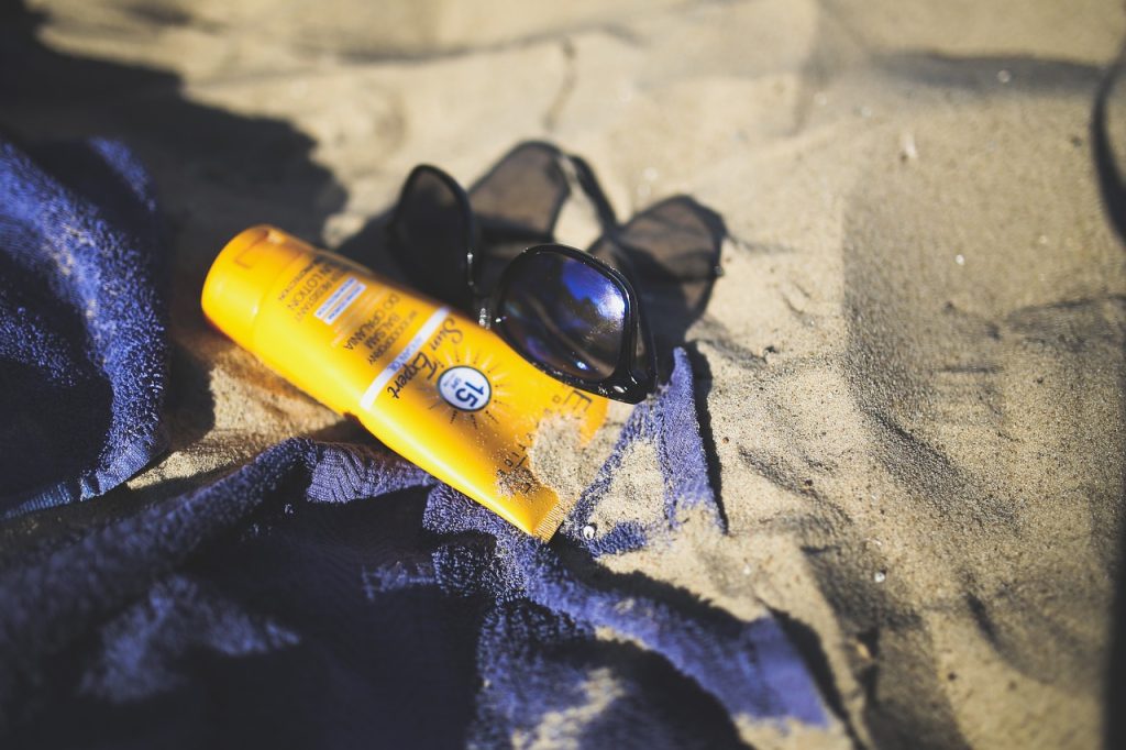 sunblock and sunglasses on sand